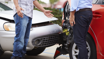 Two men stand by a car accident