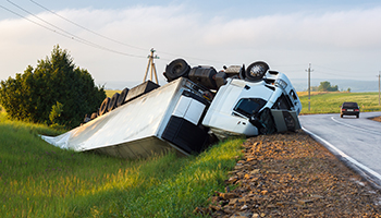 A truck is flipped over on the roadside